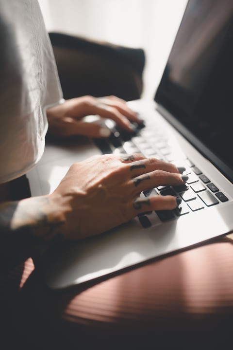 Képernyő előtt dolgozó és gépelő szakember kezei laptop billentyűzeten